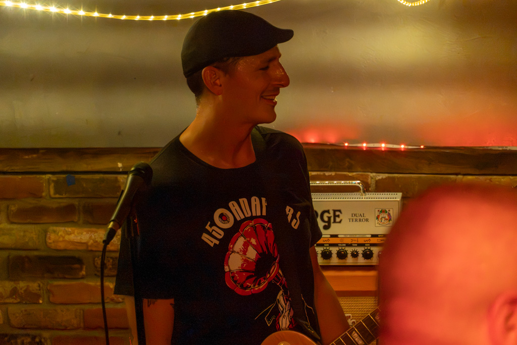 Guitarist in a cap laughing between songs