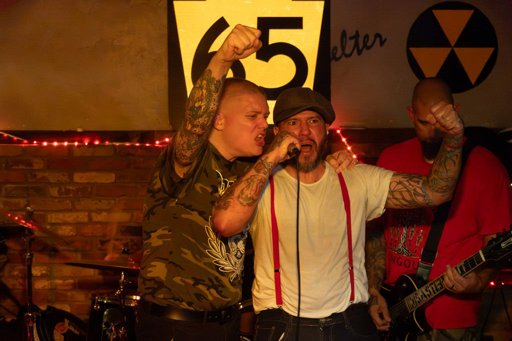 Two vocalists sharing the mic, fists raised