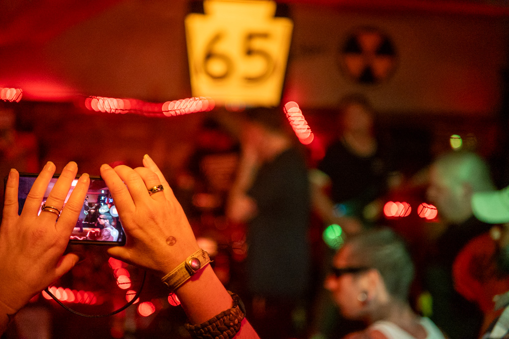 Hands raised filming the band